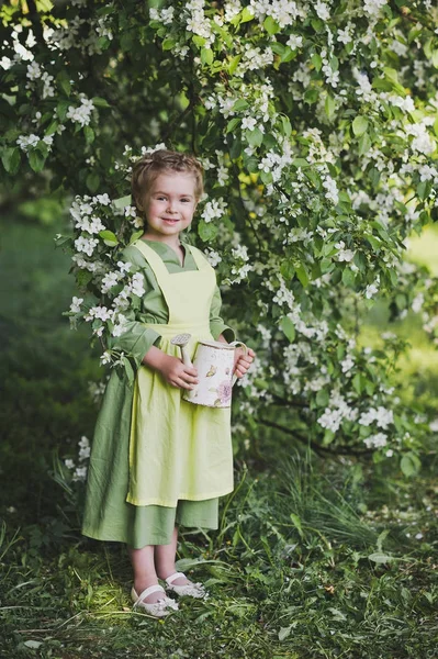 Niño con una pequeña regadera en la mano caminando en la ga primavera — Foto de Stock