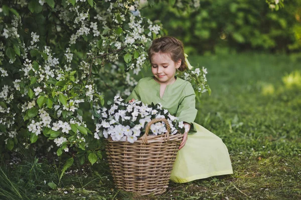 Το παιδί κάθεται κοντά σε ένα μεγάλο καλάθι λουλουδιών 8314. — Φωτογραφία Αρχείου