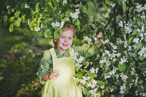 Portret dziecka stojący w pobliżu gałęzie wiśni blo — Zdjęcie stockowe