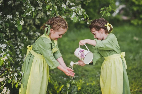 Children playing with a small watering can in the garden 8364. — Stock Photo, Image