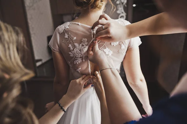 Tärnorna hjälpa bruden att bära en klänning 8480. — Stockfoto