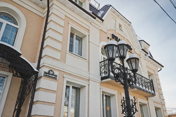 A beautiful wrought iron lantern on a background of city buildin — Stock Photo, Image