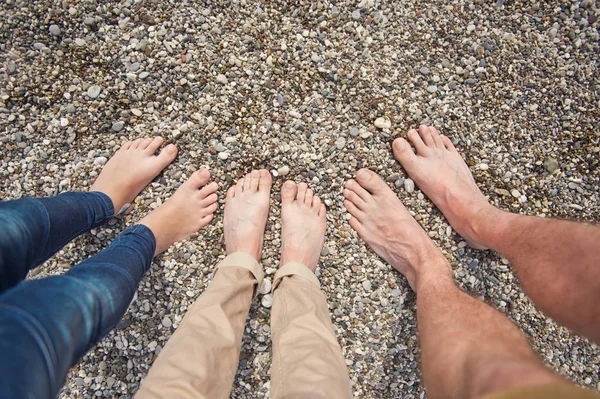 The feet of all the family members on the pebbly shore of the se — Stock Photo, Image