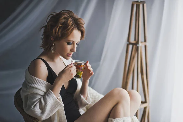 The girl drinks tea sitting in a wicker chair 8682. — Stock Photo, Image