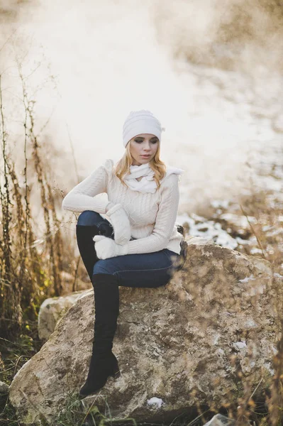 Gyönyörű lány nyugszik egy hatalmas kő, a háttérben a téli változ — Stock Fotó