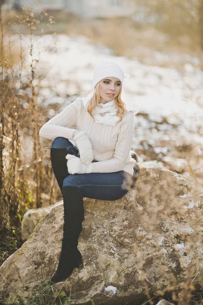 Téli portré egy lány ül egy nagy kő mellett a ro — Stock Fotó