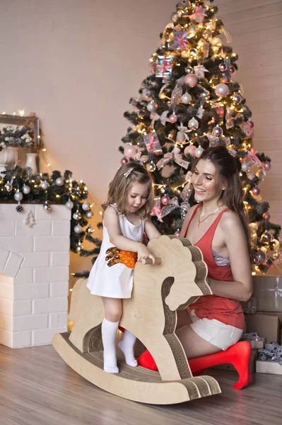 Маленькая девочка размахивает лошадью вокруг сверкающей рождественской елки 9 — стоковое фото