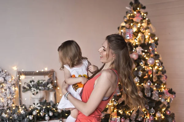Moeder draait haar dochter in haar armen op de kerstversiering — Stockfoto