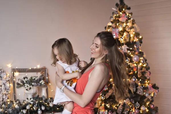 Mãe vira sua filha em seus braços sobre as decorações de Natal — Fotografia de Stock