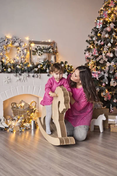 Menina em vestido rosa está montando em cavalo-balançando em torno do Christm — Fotografia de Stock