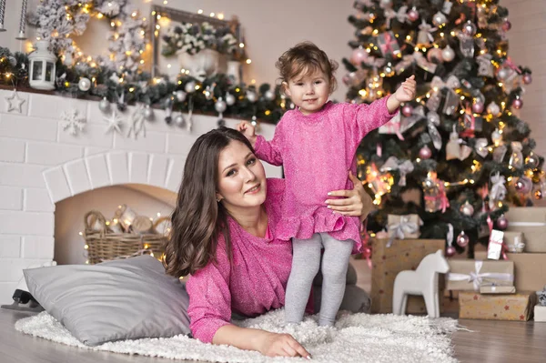 La niña y su madre tumbadas en una manta cerca de la Navidad tr — Foto de Stock