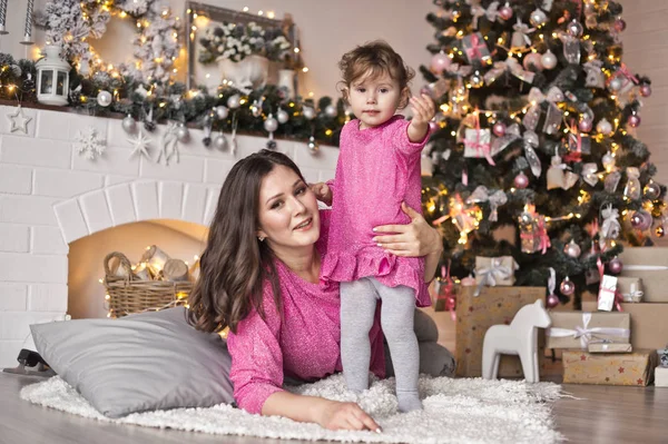 La niña y su madre tumbadas en una manta cerca de la Navidad tr — Foto de Stock