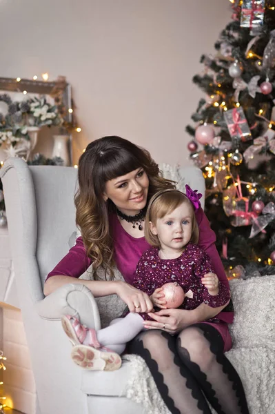 Mamá está abrazando a su hija en el fondo del árbol de Navidad — Foto de Stock