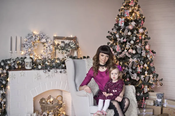 Hija y mamá sentadas en una silla cerca del árbol de Navidad 9631 — Foto de Stock