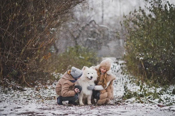 Children on a snowy path playing with the white dog 9842. — Stock Photo, Image