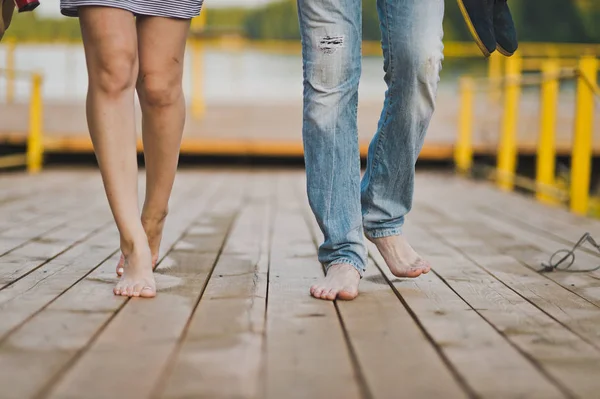 男性和女性赤脚在湖码头的行人天桥 — 图库照片