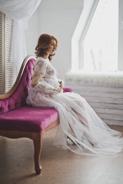 Hamile kız kanepede oturan yarı saydam bir sabahlık 