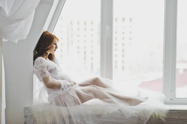 6867 pencere kenarında oturan beyaz bir elbise içinde güzel kız. — Stok fotoğraf