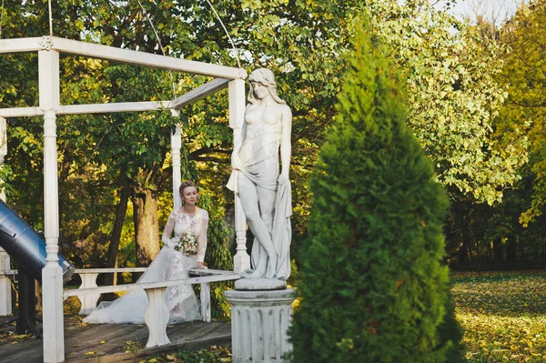 Panna Młoda w białej sukni siedzi na ławce w ogrodzie 248. — Zdjęcie stockowe