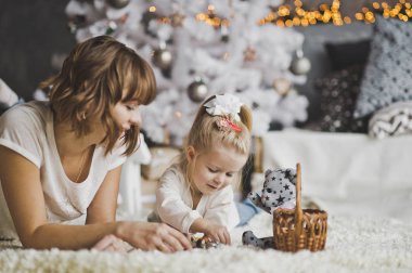 Anne ve kızı beyaz dekore edilmiş Ch altında halı üzerinde yalan