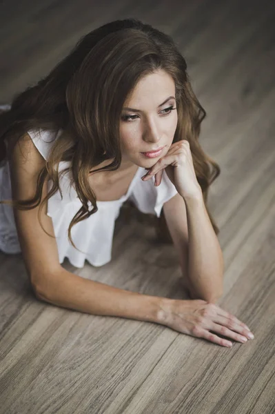 A girl with long brown hair posing on the parquet floor 6934. — Stock Photo, Image