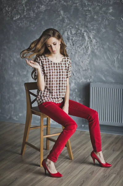 Young girl in red jeans was sitting on a chair 6936. — Stock Photo, Image