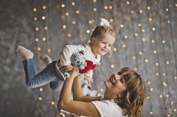 Mutter wirft Tochter auf den Hintergrund funkelnder Lichter — Stockfoto