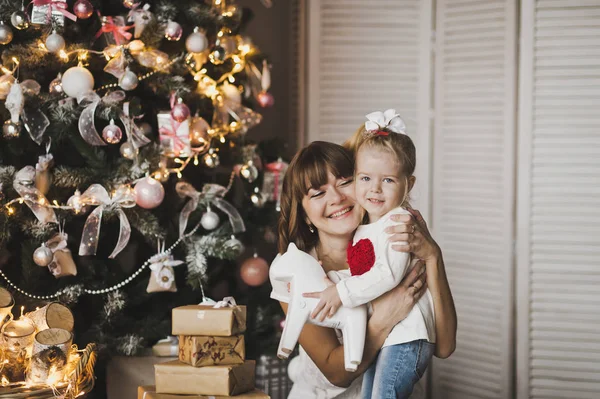 Boldog anya és lánya, a háttérben a karácsonyi játék — Stock Fotó