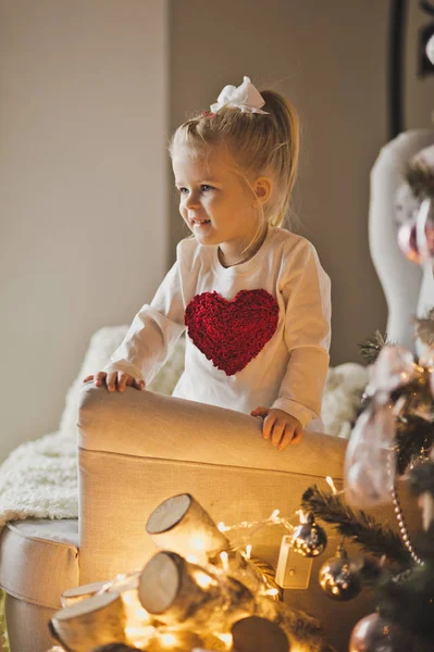 The child plays with the ornaments on the Christmas tree 7277. — Stock Photo, Image