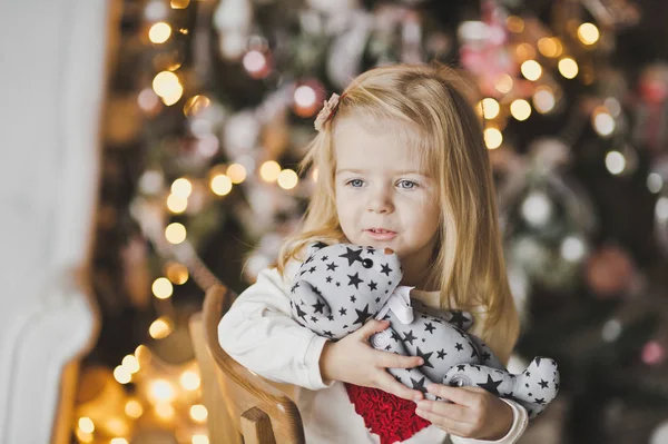 Una niña sentada cerca del árbol de Navidad en espera de una mi — Foto de Stock