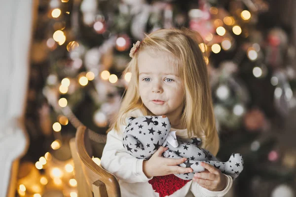 一个小女孩坐在圣诞树旁期待着一颗蜜 — 图库照片