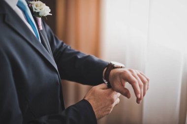 Takım elbiseli bir adam bir saat kolunda 716 giyer..