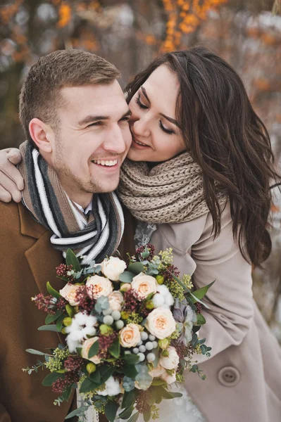 Os recém-casados sorriem felizes em um passeio de inverno entre as bagas o — Fotografia de Stock