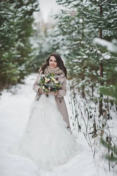 Portrait d'une mariée en robe blanche chic parmi les sapins enneigés — Photo