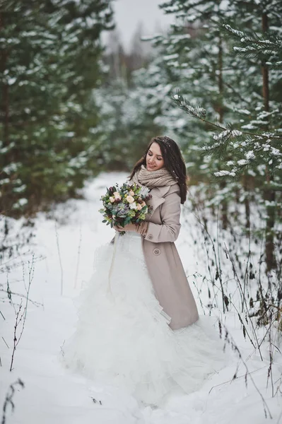 Portrait d'une mariée en robe blanche chic parmi les sapins enneigés — Photo