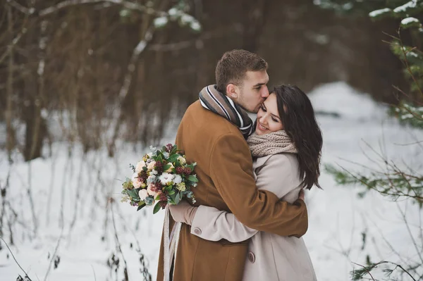 Forte étreinte douce des jeunes mariés sur fond d'hiver — Photo