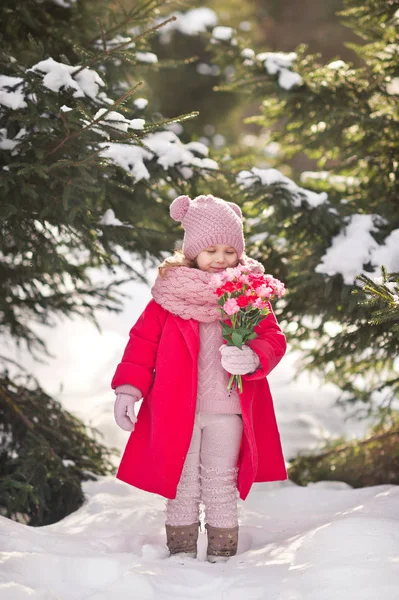 Het kind met bloemen op de achtergrond van snowcovered vuren f — Stockfoto