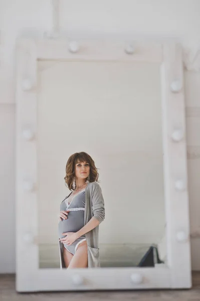 En smuk gravid pige beundrer hendes figur i spejlet 1096 . - Stock-foto