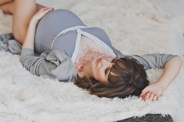 A pregnant girl lies among white furs 1103. — Stock Photo, Image