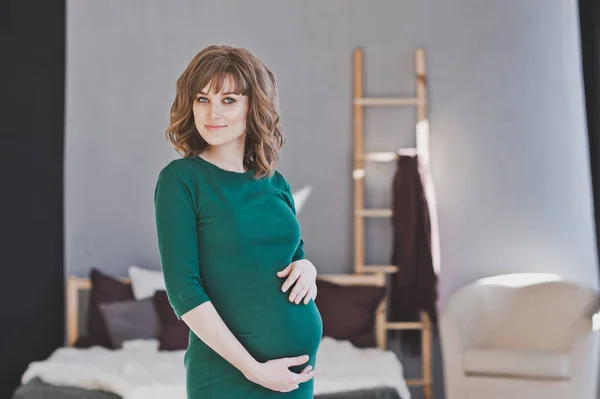 Μια έγκυος κοπέλα σε ένα πράσινο φόρεμα που στέκεται ανάμεσα στο δωμάτιο 1111. — Φωτογραφία Αρχείου