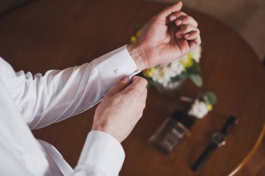 Genç adam bir düğme beyaz gömlek 11 koluma takılır.