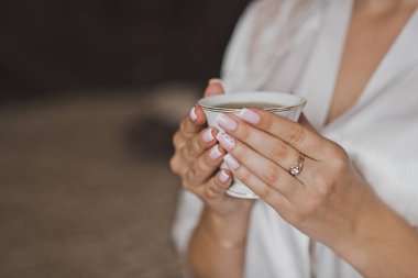 2153 numaralı sabahlık giymiş bir kızın elinde bir fincan çay..