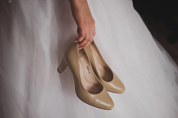 La mariée dans une robe blanche tenant des chaussures beiges 2276. — Photo
