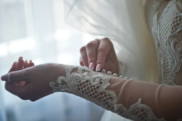 The bride fastens the buttons on the sleeve of the dress 2375. — Stock Photo, Image