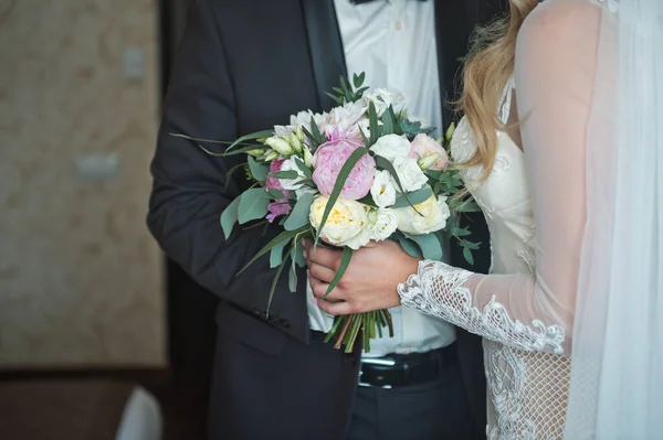 La mariée embrasse doucement le marié tenant un bouquet dans un han — Photo