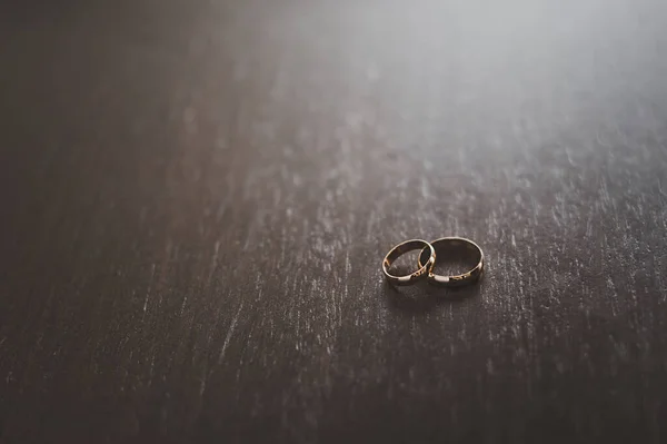 Dois anéis de casamento em uma mesa de madeira escura. — Fotografia de Stock