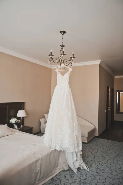 Un vestido de novia en una lámpara de araña en medio de una hermosa roo —  Fotos de Stock