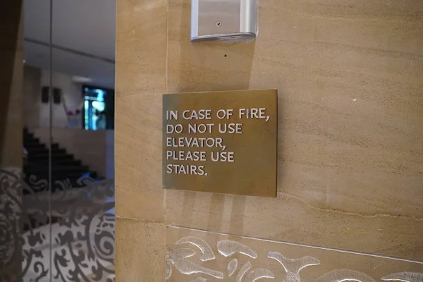 En skylt som säger, I händelse av brand, Använd inte hiss, Använd Trappor, som styr människor vad de ska göra i händelse av en brand nödsituation. — Stockfoto
