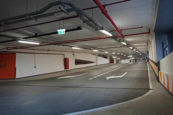 Steep paving descent to the parking lot. Brand new descending roads inside parking lot. Indoor parking lot exit passage perspective. Double lane.