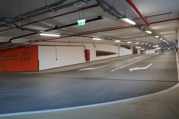 Steile bestrating afdaling naar de parkeerplaats. Gloednieuwe afdalende wegen op de parkeerplaats. Overdekte parkeerplaats uitgang perspectief. Dubbele rijstrook. — Stockfoto